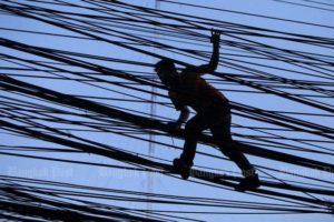This worker is able to cut through the tangle to install internet connection lines along Sarasin Road in Bangkok but the ICT ministry has failed to organise an auction to move ahead the national broadband project.